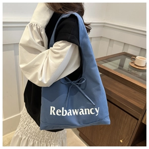 Detailed close-up of blue canvas tote bag featuring white Rebaancy text and drawstring bow