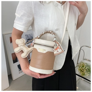 Detail of cylinder bucket bag with crocodile texture, silk scarf handle and puppy charm