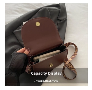 Brown saddle bag showing internal storage capacity and geometric patterned strap
