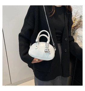 Détail du mini sac blanc en forme de coquille avec texture litchi et breloque lapin