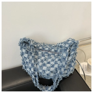 Close-up of blue and white checkered denim bag with fringe trim and wide shoulder strap