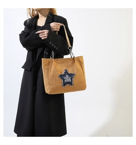Close-up of brown corduroy tote bag with denim star patch and chain leather strap