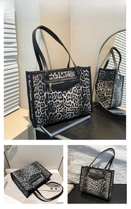 Detail view of leopard print tote bag with black leather zipper pocket and sturdy handles