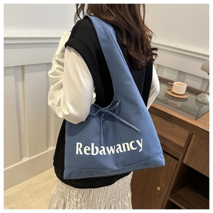 Detail of blue canvas tote bag featuring Rebawancy lettering and side drawstring design