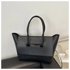 Detailed view of black minimalist tote bag featuring a flip-top closure and matte leather