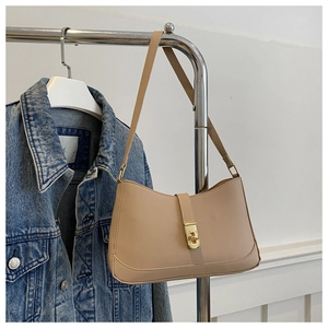 Detail of beige faux leather baguette bag featuring a gold twist lock and slim strap