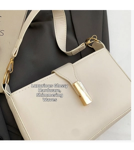 Close-up of cream leather shoulder bag with glossy gold rectangular buckle detail