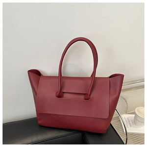 Detail of burgundy leather tote bag side wing structure on an armchair