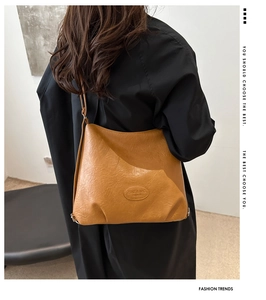 Close-up of the embossed logo and pebbled leather texture on a brown hobo tote bag