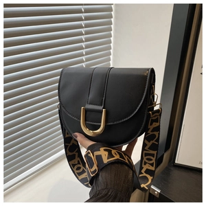 Close-up of black saddle bag featuring gold U-shaped metal buckle and lettered strap