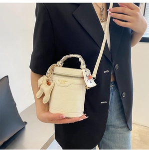 Close-up of cream crocodile pattern cylinder bag with silk scarf and rabbit charm