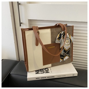 Detail shot of a contrast color tote bag with a fashion print scarf on a book