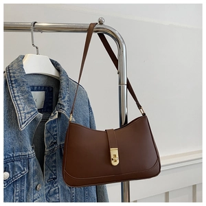 Detail of dark brown leather shoulder bag with gold twist lock on denim background