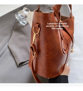Détail d'un sac seau en cuir marron avec garniture dorée et un pendentif smiley mignon