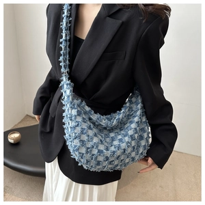 Close-up of blue and white checkered denim crossbody bag featuring fringe edges