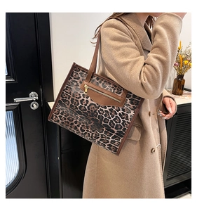 Close-up of leopard print tote bag with brown leather details and gold zipper accents