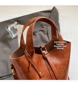 Détail d'un sac seau vintage en cuir PU marron avec double poignées et boucles dorées