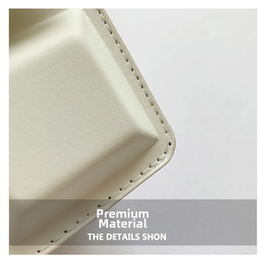 Detailed macro view of cream-colored leather texture and fine stitching on a shoulder bag