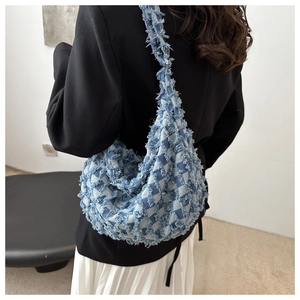 Detail of blue and white checkered denim bag featuring distressed fringe edge details