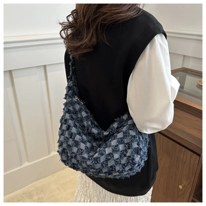 Detailed close-up of blue checkerboard denim hobo bag with trendy raw fringe edges