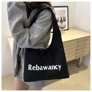 Detail of black canvas tote bag with Rebawancy print and a delicate bow decoration