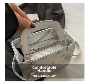 Detail of silver-grey printed tote bag with smooth handles and silver-tone hardware