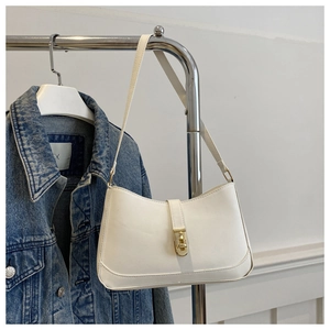 Close-up of white leather underarm bag with gold twist lock hanging on a metal rack