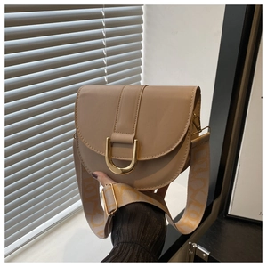 Detail of a beige saddle bag with a golden horseshoe buckle and jacquard woven strap