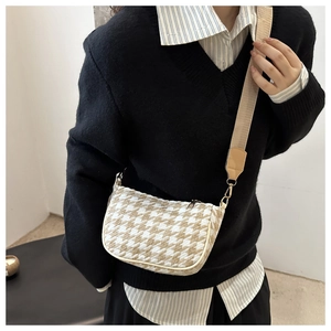 Close-up of houndstooth crossbody bag with wide strap and gold hardware detail
