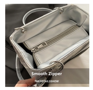 Detail view of smooth silver handbag interior with high-quality metal zipper pocket