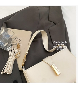 Detail of cream rectangular handbag with gold metal clasp and adjustable strap