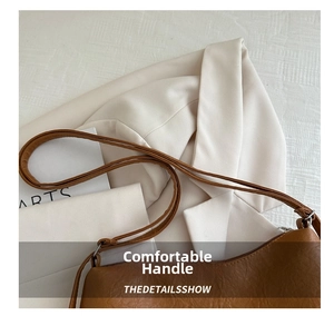 Close-up of caramel leather tote bag with silver zipper and adjustable strap detail