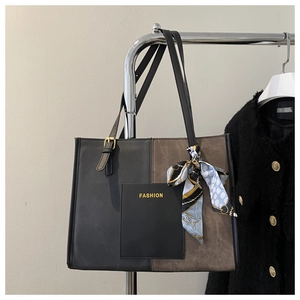 Detail of a color-block tote bag with FASHION logo and silk scarf on a tweed jacket