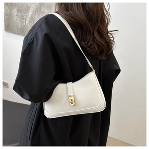 Close-up of white leather underarm bag with gold rotating lock on a model's shoulder