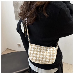 Houndstooth crossbody bag with round coin purse detail and wide strap worn on shoulder