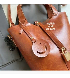 Détail du sac seau en cuir marron avec breloque smiley et cadenas doré sur une veste