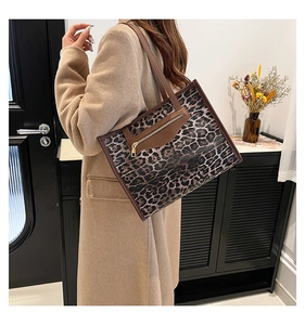 Leopard print tote bag detail showing brown leather zipper pocket and stylish long strap