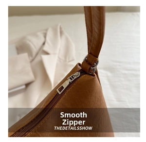 Close-up of smooth metal zipper and premium leather texture on a brown tote bag