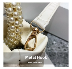Close-up of pearl woven handle and gold hardware hook on a white cloud bag