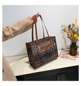 Close-up of leopard print tote bag featuring brown leather handles and a zipper detail