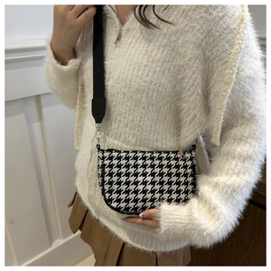 Detail of houndstock pattern crossbody bag with wide black shoulder strap and gold hardware