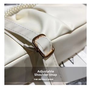 Detail of adjustable leather shoulder strap with gold metal buckle on beige cloud bag