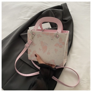 Detail of pink butterfly pattern and silver metal hardware on a white mini handbag