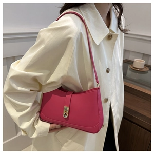 Detail of rose pink leather underarm bag featuring a metallic gold twist-lock closure