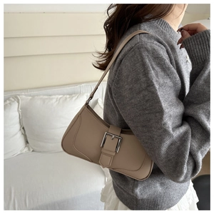 Dettaglio di una borsa baguette in pelle opaca beige con fibbia d'argento sotto l'ascella