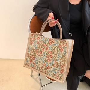 Detail of floral canvas tote bag with dense pastel flower patterns and sturdy handles