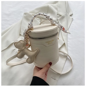 Detail of white crocodile pattern cylinder bag with silk scarf handle and bear charm