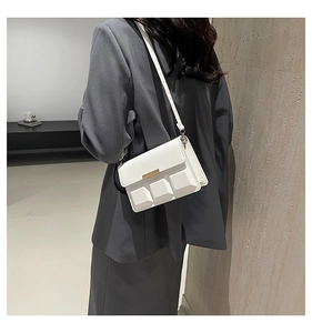 Detailed side view of white faux leather crossbody bag with 3D square patterns and gold trim