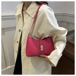Detailed view of magenta faux leather shoulder bag with gold metal buckle on model
