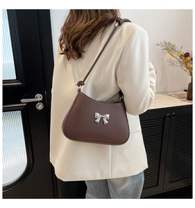 Détail d'un sac porté épaule marron foncé avec noeud en métal argenté et bandoulière